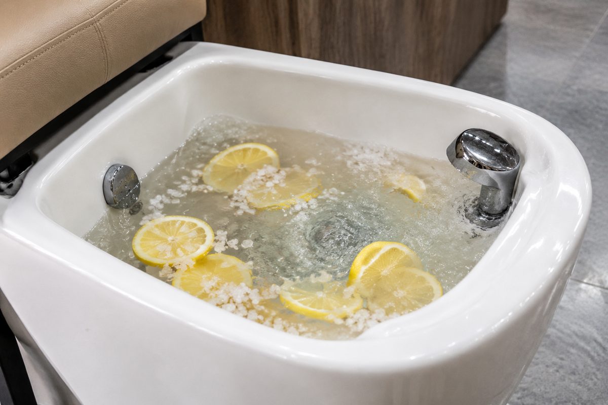 White ceramic pedicure foot bath filled with warm water and natural sea salt crystals